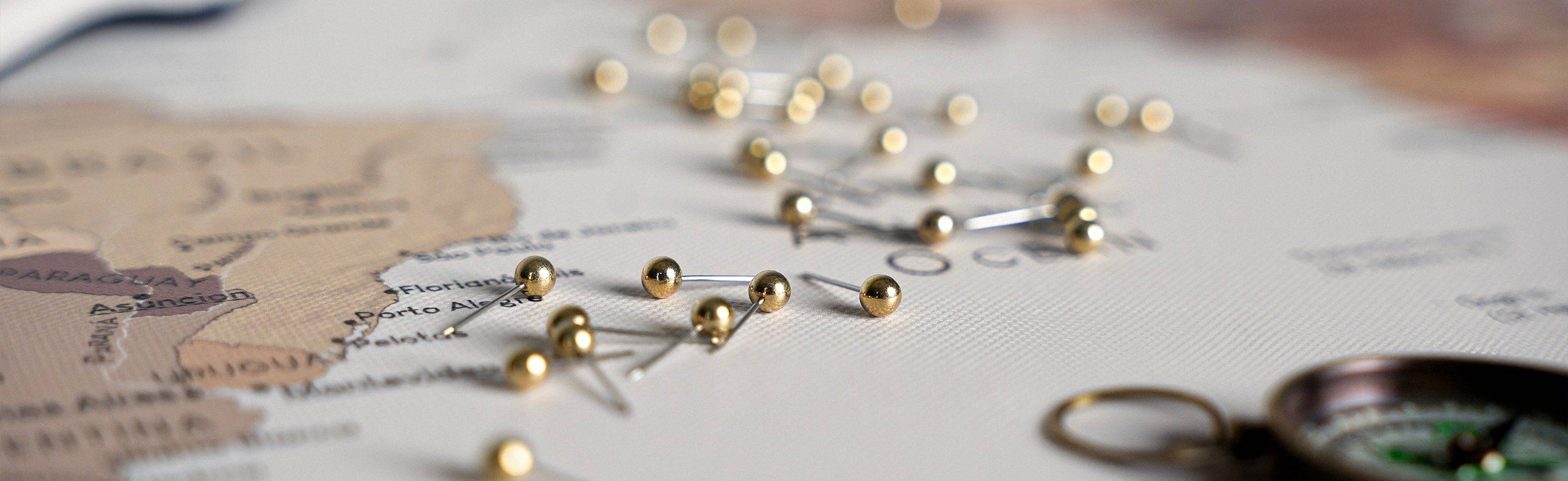 Close-up of golden push pins on a world map canvas highlighting various travel destinations, ideal for travel enthusiasts and as a wall art piece – world map pinboard for planning and tracking global adventures.