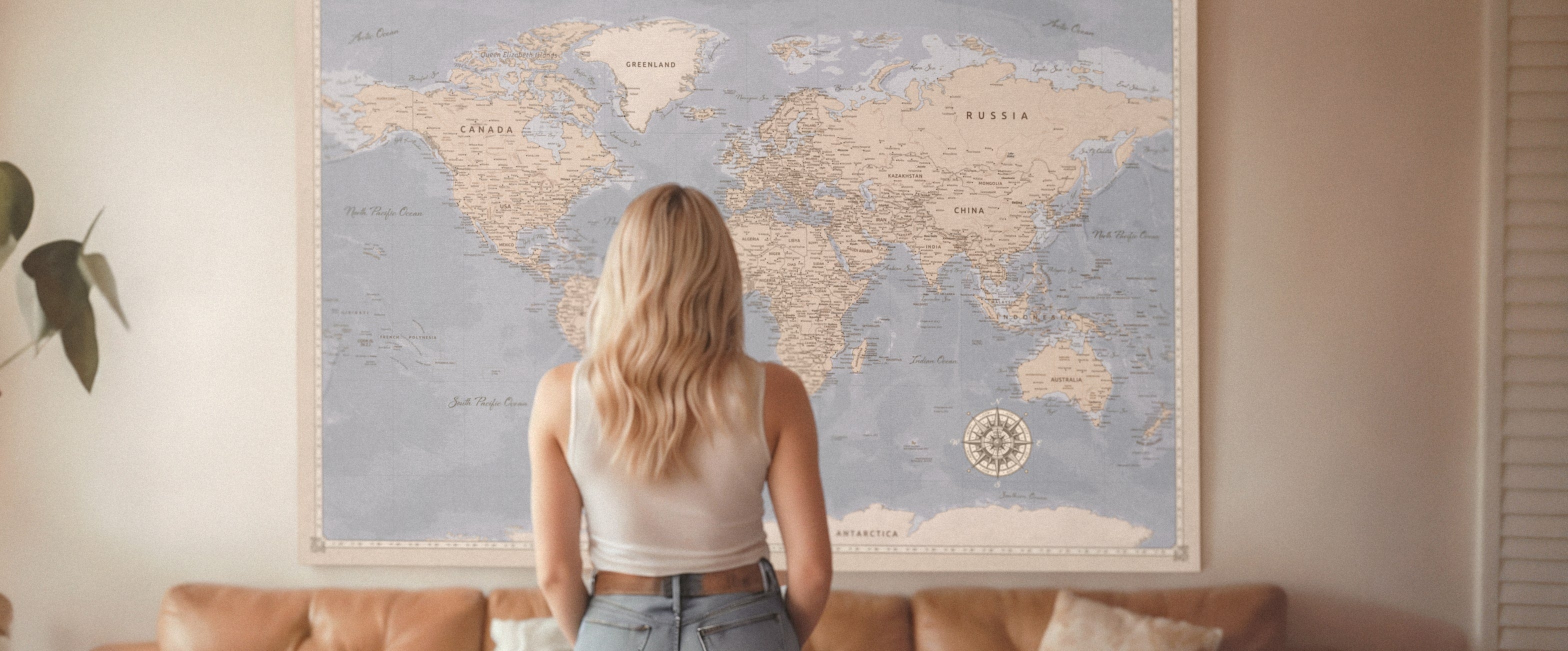 Femme blonde regardant un grand tableau d'affichage de carte du monde personnalisé pour les voyageurs sur le mur, cadeau parfait pour les voyageurs, tableau en liège avec punaises.