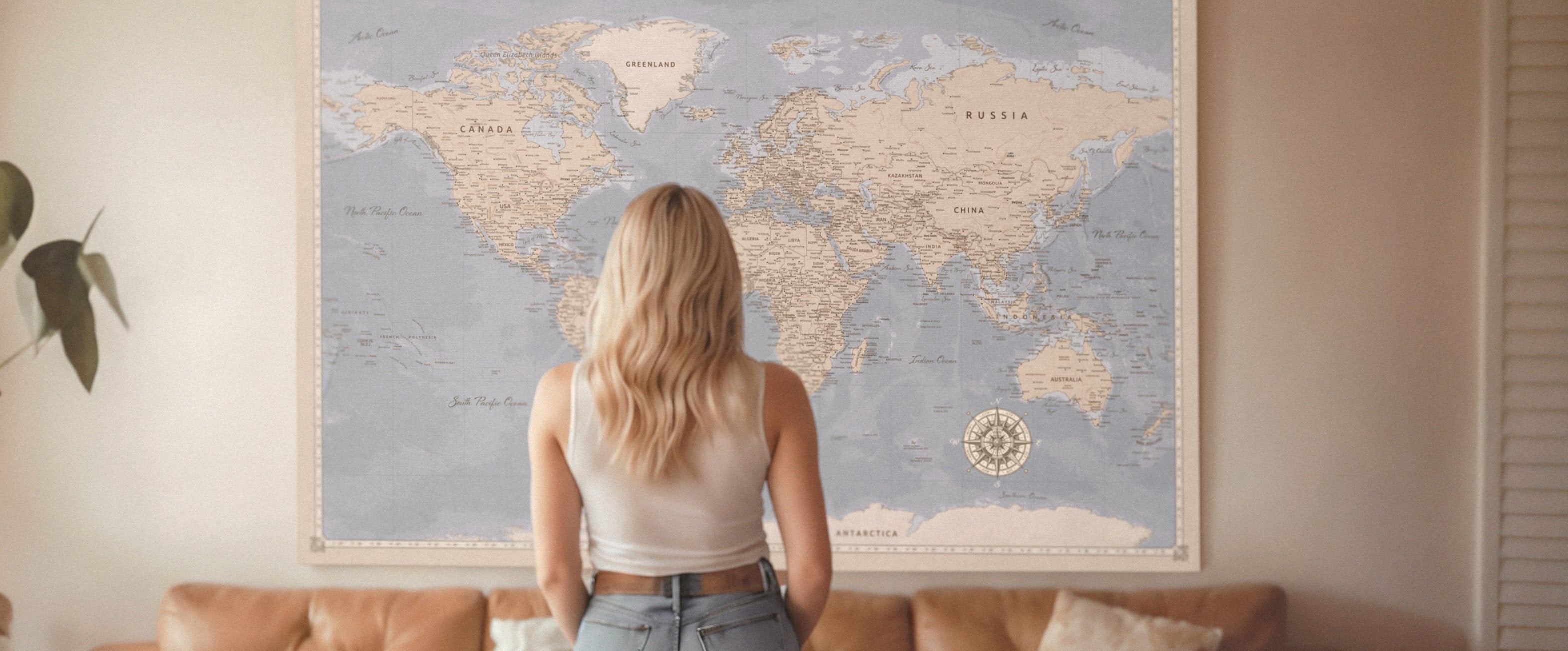 Blonde woman looking at a large personalised travel world map pinboard on the wall, perfect gift for travellers, pushpin cork board.