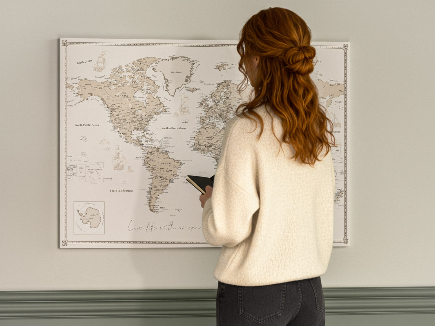 Woman looking at framed world push pin travel map wall art in a modern living room